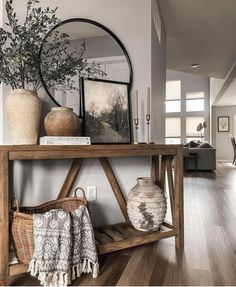 a wooden table with vases on top of it next to a mirror and pictures