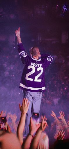 a man standing on top of a stage with his arms in the air and hands raised