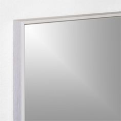 a bathroom mirror mounted on the wall with a white frame and silver trim around it