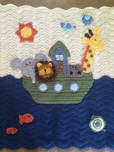 a crocheted baby blanket with animals in a boat and fish on the water