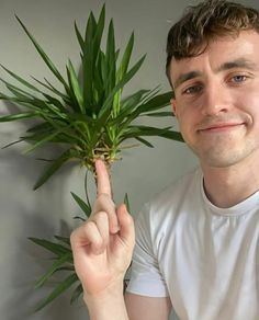 a man holding up a plant in front of his face and pointing to the camera