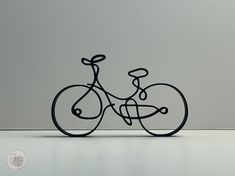 a metal bike sculpture sitting on top of a white table next to a gray wall