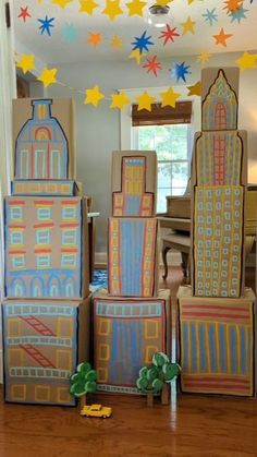 cardboard buildings are stacked on top of each other in front of a mirror with stars hanging from the ceiling