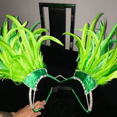 a person wearing green feathered headpieces on top of a black table next to a chair