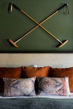 a bed topped with pillows and two wooden mallets mounted to the wall above it