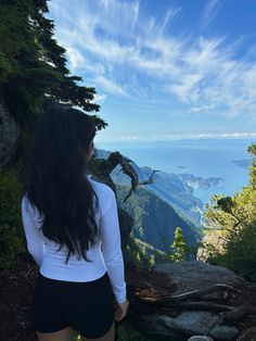 a woman standing on top of a mountain looking at the ocean