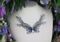 A must-have for all fairies! A truly beautiful transparent purple statement necklace, adorned with gems and a dash of sparkle. The wings are backed with wire for support and to keep their lovely shape. The necklace measures approximately 12cm across. This delicate array of fairy wings is really rather lovely. It is perfect for all fairy lovers - whether to be worn as part of a costume, or simply as a statement necklace for everyday wear. It is super light weight, and flexible to touch (please don't bend, however!) Please note that the wings may grow cloudy/opaque over time when exposed to sunlight, heat, perspiration and makeup. The wings should also avoid contact with water.  The chain measures approximately 17 inches in length. However, the chain can be made longer or shorter if you wish Purple Fairycore Jewelry For Party, Purple Whimsical Necklace For Party, Fairycore Purple Necklace For Gift, Whimsical Purple Necklace For Party, Fairycore Butterfly Necklace Gift, Iridescent Fairy-style Jewelry For Parties, Iridescent Fairy Jewelry For Parties, Iridescent Fairy Style Jewelry For Party, Purple Statement Necklace