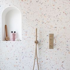 a bathroom with white walls and colorful speckles on the wall, including a shower head