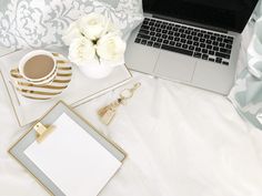 an open laptop computer sitting on top of a bed next to a cup of coffee