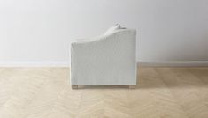 a white couch sitting on top of a hard wood floor next to a wall and window