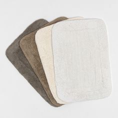 four bath mats in various colors on a white background