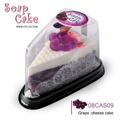 a piece of cake in a plastic container on top of a black stand with purple and white frosting