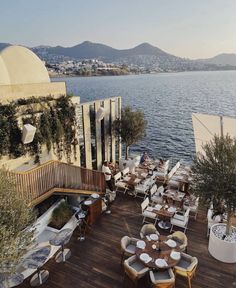 an outdoor dining area overlooking the water with tables and chairs set up for people to eat