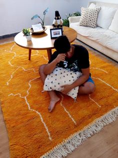 a man sitting on the floor in front of a rug