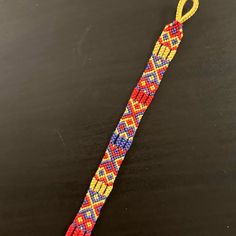 an orange, yellow and blue beaded bracelet on a black surface