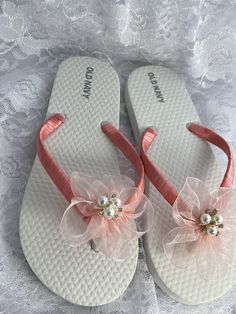 These beautiful white flip flops are hand wrapped in a coral satin ribbon, and adorned with a handmade light coral organza flower with pearls and rhinestones center.  Ribbon color is coral if you are needing other colors of ribbon or decoration please contact me and will be happy to accommodate you! Can also me made is child size 12/13, 1/2, 3/4 and 5. All flip flops are handmade to order and the production time is 5-7 business days and then please allow additional time for shipping. Amazing for Adjustable Pink Sandals For Wedding, White Flip Flops For Beach Season Parties, Elegant Pink Summer Flip Flops, Elegant Flower-shaped Beach Sandals, White Summer Flip Flops For Party, White Summer Party Flip Flops, White Sandals For Spring Gift, White Sandals As Spring Gift, White Flower Shaped Sandals For Beach