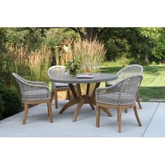 an outdoor table and chairs set up on a patio with grass in the back ground