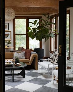 a living room filled with furniture and windows next to a plant on top of a table