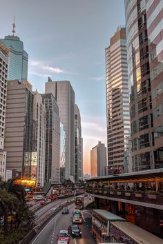 a city street filled with lots of traffic next to tall buildings in the evening sun