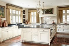 a large kitchen with white cabinets and black counter tops, an island in the middle