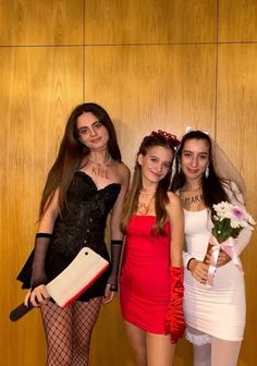 three young women dressed up in costume posing for a photo with one holding a bouquet