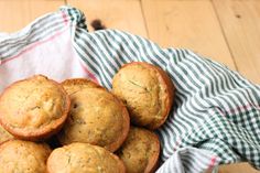 a basket filled with muffins sitting on top of a wooden table next to a green and white checkered cloth