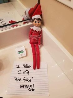 an elf is sitting in the sink with a note attached to it that says i think i did the floss wrong