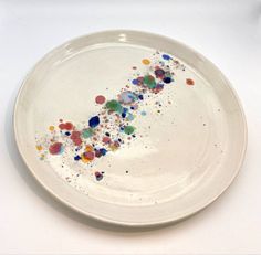 a white plate with multicolored sprinkles on the rim and bottom