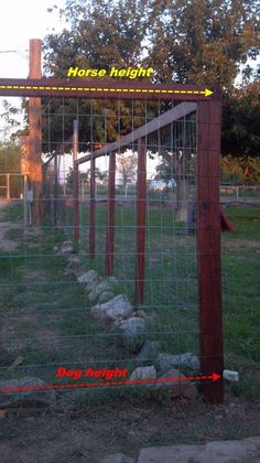 there is a horse fence in the yard with rocks and grass behind it that has an arrow pointing to the right