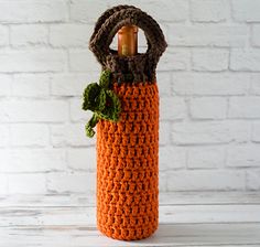 an orange crocheted bag with a green plant in it