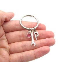 a person holding a keychain with the letter p on it's side