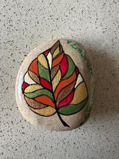 a painted rock with a leaf on it