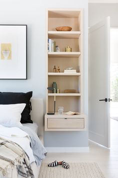 a bedroom with a bed, nightstand and bookshelf next to a white door