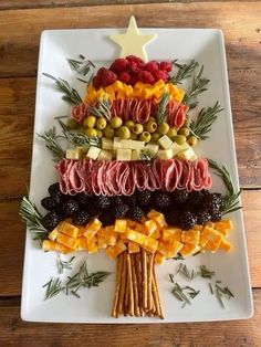 a christmas tree made out of fruits and vegetables on a white platter with olives