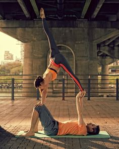 two people doing yoga poses in front of a bridge