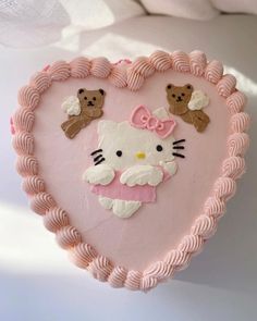 a cake shaped like a heart with hello kitty on it's face and teddy bears in the middle