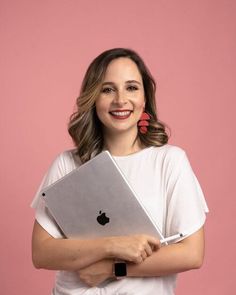 a woman is holding an apple laptop in her arms and smiling at the camera with both hands