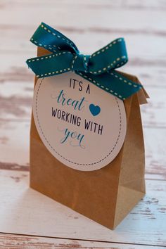 a brown paper bag with a blue ribbon on it that says it's a treat working with you