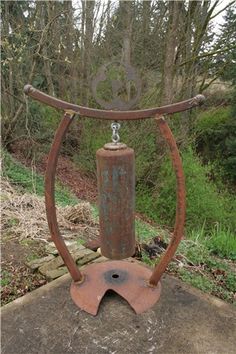 an old rusted metal object sitting on top of a cement slab in the woods