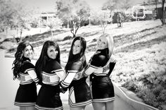 three young women in cheerleader outfits posing for a black and white photo with trees in the background