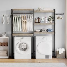 a washer and dryer in a room with clothes hanging on the rack next to each other