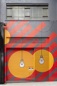 a garage door painted with bright colors and hanging lightbulbs