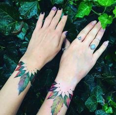 two women's hands with tattoos on their arms and one has a leaf tattoo