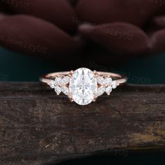 an oval diamond ring with three smaller round diamonds on the band, set in 18k rose gold