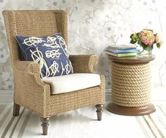 a wicker chair with blue and white pillows next to a vase on a table