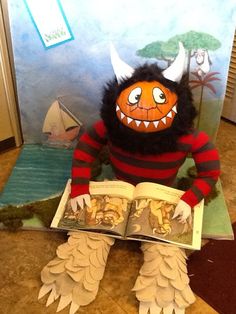 a stuffed animal sitting on the floor reading a book with an open mouth and teeth