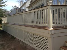 a wooden deck with white railings next to a house