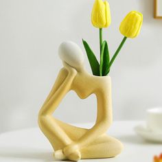 a vase with yellow flowers in it sitting on a table