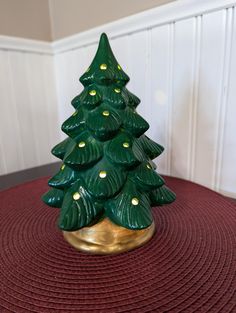 a green ceramic christmas tree sitting on top of a red rug