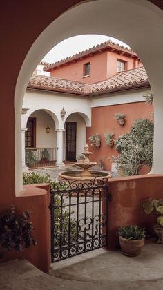 an archway leading into a courtyard with potted plants